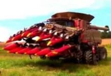 A large red harvester with front attachments sits in a field, showcasing the latest in farming technology and ready for work.