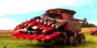 A large red harvester with front attachments sits in a field, showcasing the latest in farming technology and ready for work.