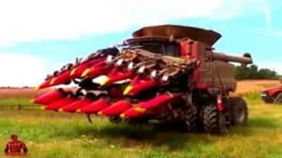 A large red harvester with front attachments sits in a field, showcasing the latest in farming technology and ready for work.