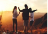 Four people stand on a hilltop at sunset, arms raised, overlooking a scenic view. How does your life shape your age