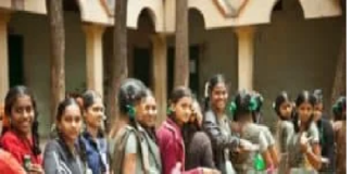 A group of middle class school students in uniform stands in a line outdoors, holding items in their hands, with trees and a building in the background.