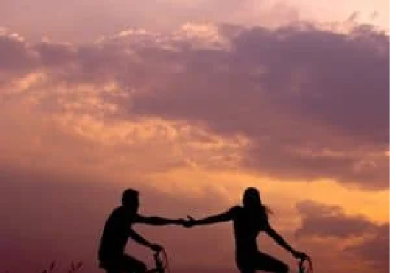 Two people on bicycles hold hands against a sunset sky. Our life