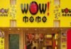 Front entrance of "Wow! Momo" restaurant with bright yellow signage and a staff member visible at the counter inside.