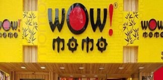 Front entrance of "Wow! Momo" restaurant with bright yellow signage and a staff member visible at the counter inside.