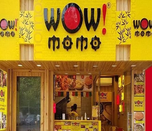 Front entrance of "Wow! Momo" restaurant with bright yellow signage and a staff member visible at the counter inside.