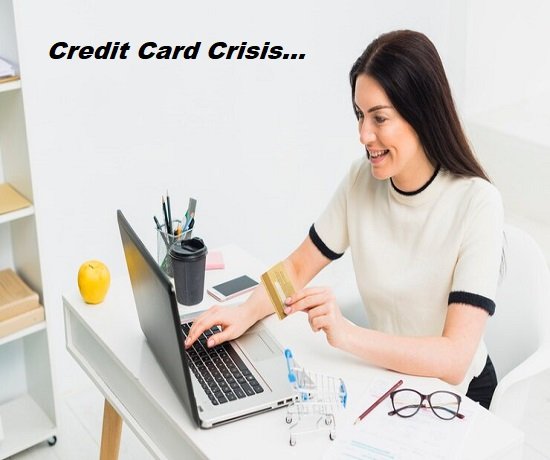 A woman sits at a desk holding a credit card while using a laptop, contemplating her mounting credit card debt. Text reads "Credit Card Crisis...