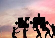 Silhouettes of people working together to fit giant puzzle pieces against a sunset background, embodying the spirit of challenges and personality development.