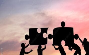 Silhouettes of people working together to fit giant puzzle pieces against a sunset background, embodying the spirit of challenges and personality development.