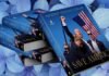 Stack of books titled "Save America" with a cover image featuring a man holding an American flag against a background of blue hydrangeas.