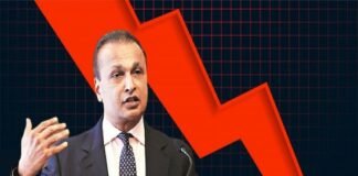 A man in a suit, possibly channeling Anil Ambani insightful demeanor, gestures while speaking, with a prominent red downward arrow in the background.