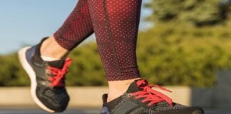 A person in red patterned leggings strides confidently on a stone surface, sporting black and red sneakers, perhaps the best running shoes for flat feet.