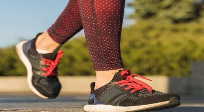 A person in red patterned leggings strides confidently on a stone surface, sporting black and red sneakers, perhaps the best running shoes for flat feet.