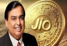 A smiling man in a suit stands proudly in front of a large Jio Coin, its embossed, circuit-like design gleaming with innovation.