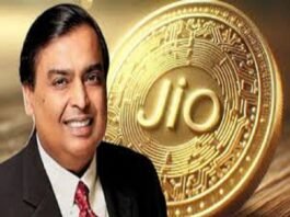 A smiling man in a suit stands proudly in front of a large Jio Coin, its embossed, circuit-like design gleaming with innovation.